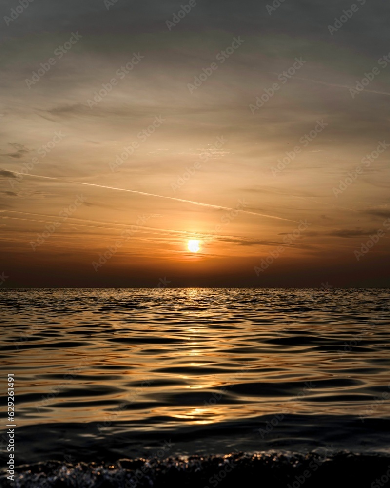 Obraz premium the sun is setting over the ocean at dusk on the beach