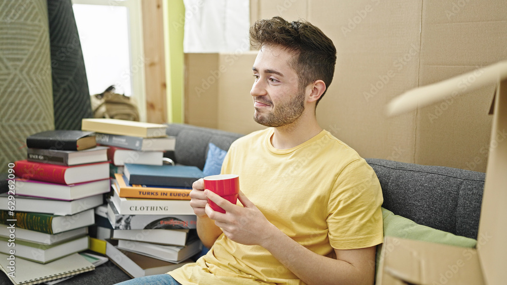 Young hispanic man smiling confident drinking coffee at new home