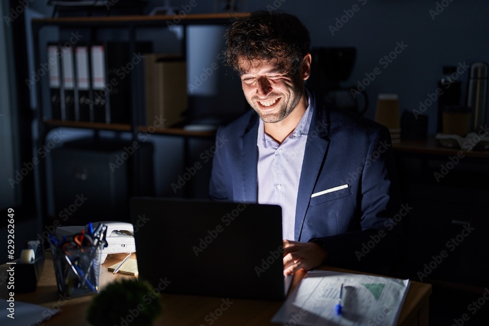 Hispanic young man working at the office at night winking looking at the camera with sexy expression, cheerful and happy face. Hispanic young man working at the office at night winking looking at the camera with sexy expression, cheerful and happy face.