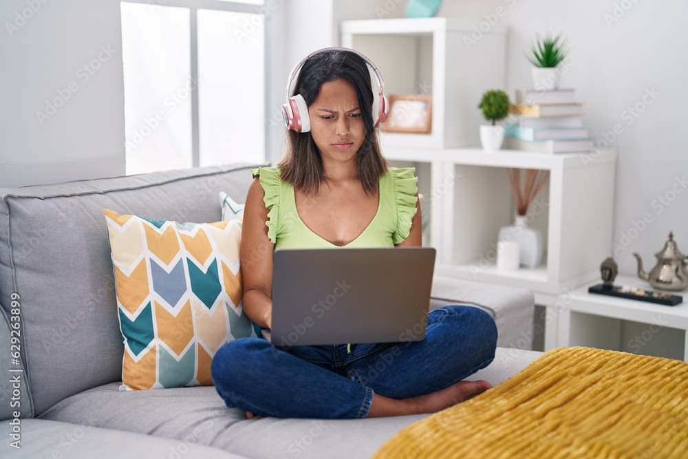 Hispanic young woman using laptop at home skeptic and nervous, frowning upset because of problem. negative person. Hispanic young woman using laptop at home skeptic and nervous, frowning upset because of problem. negative person.
