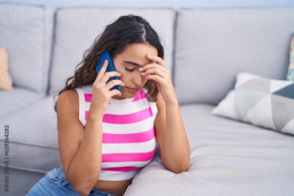 Young beautiful hispanic woman talking on smartphone with worried expression at home Young beautiful hispanic woman talking on smartphone with worried expression at home