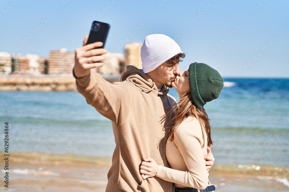 Mand and woman couple hugging each other and kissing make selfie by smartphone at seaside