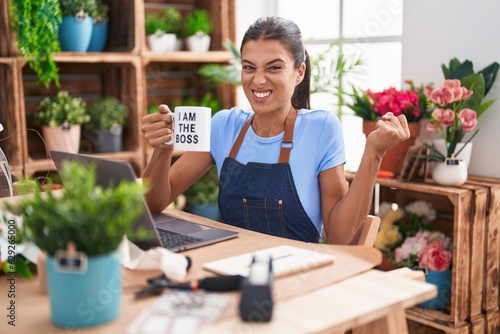 Brunette young woman working at florist shop holding i am the boss cup screaming proud  celebrating victory and success very excited with raised arm