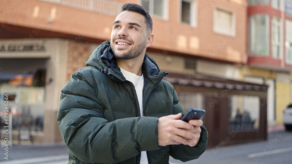Young hispanic man smiling confident using smartphone at coffee shop terrace Young hispanic man smiling confident using smartphone at coffee shop terrace