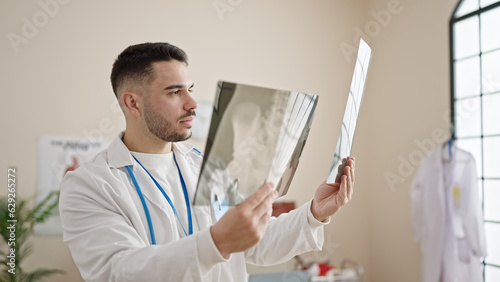 Young hispanic man doctor looking xray at clinic