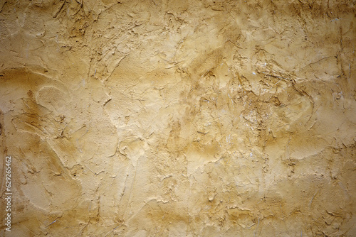 The photo captures a wall painted with yellow-colored earth, with a rough and textured surface