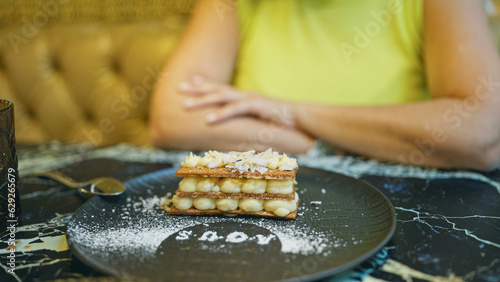 Middle age hispanic woman eating milhoja as dessert in a restaurant