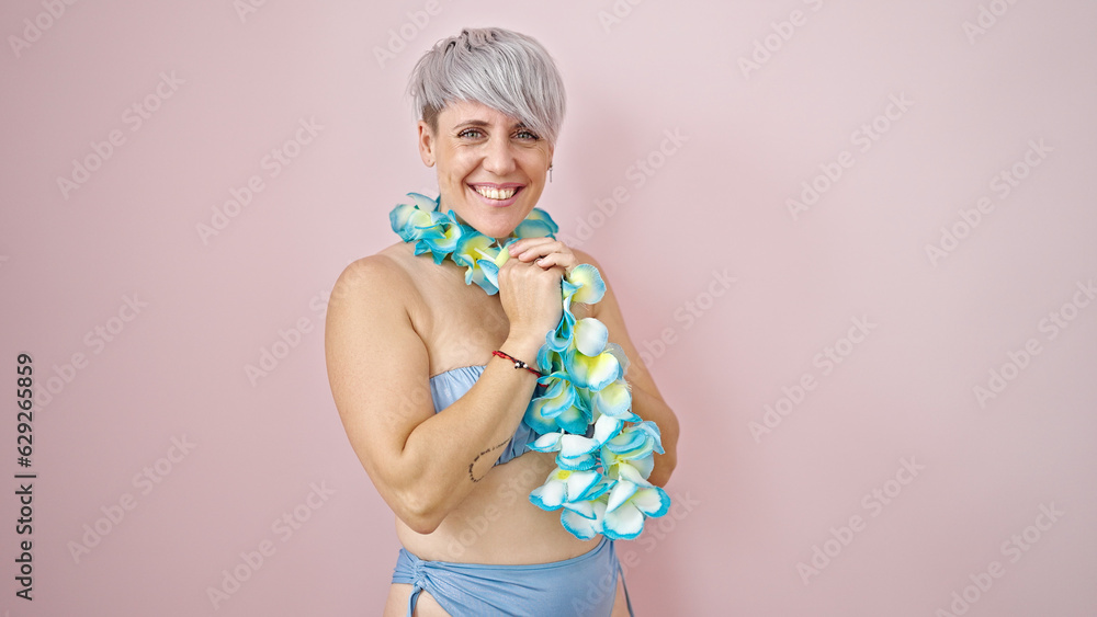 Young woman tourist wearing bikini and hawaiian lei smiling over isolated pink background Young woman tourist wearing bikini and hawaiian lei smiling over isolated pink background