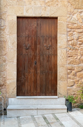 Traditional, wooden entrance door with a detailed stone frame.