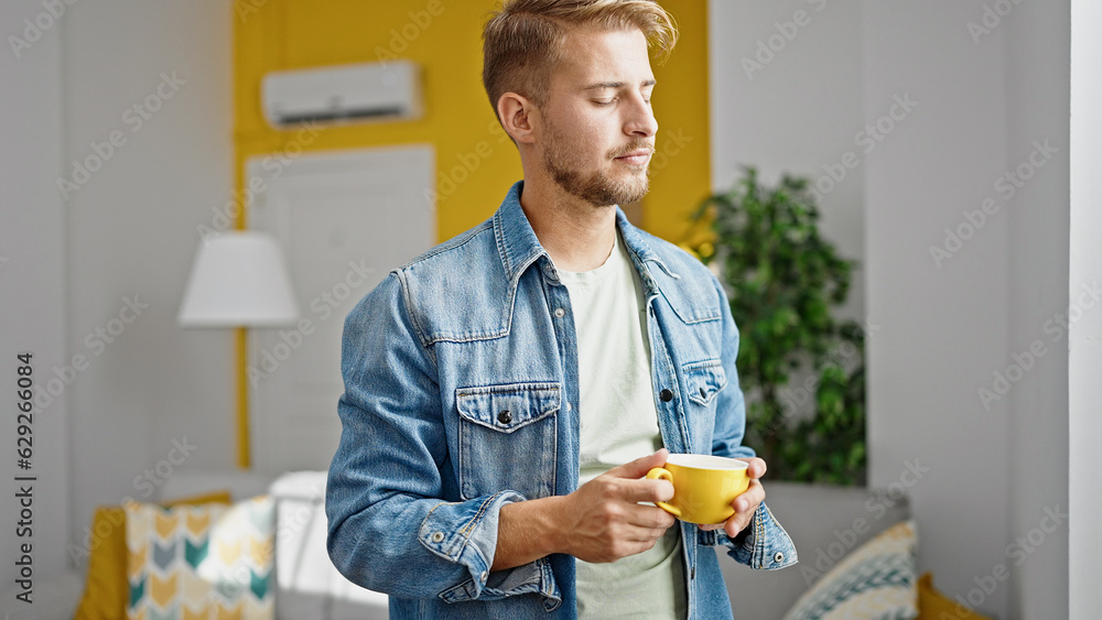 Young caucasian man drinking coffee standing at home Young caucasian man drinking coffee standing at home