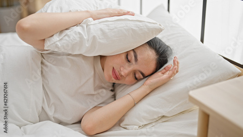 Young beautiful hispanic woman covering ears for noise at bedroom