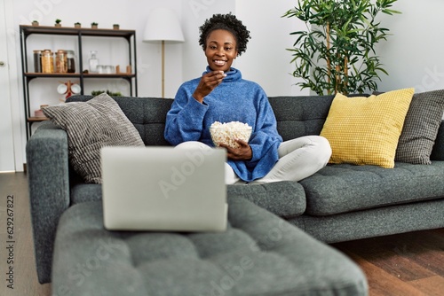 African american woman watching movie sitting on sofa at home