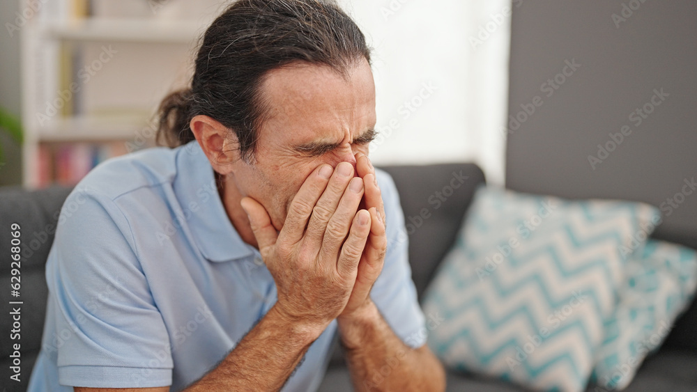 Middle age man stressed sitting on sofa at home Middle age man stressed sitting on sofa at home