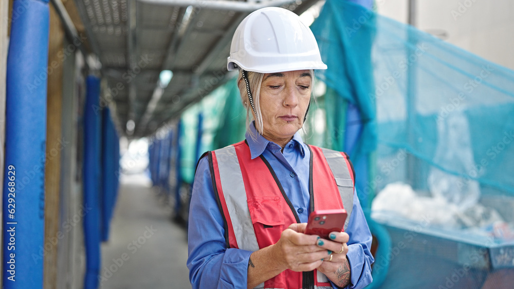 Middle age grey-haired woman builder using smartphone at street Middle age grey-haired woman builder using smartphone at street