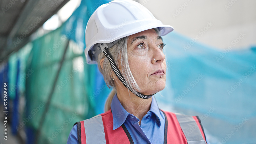 Middle age grey-haired woman builder standing with relaxed expression at street Middle age grey-haired woman builder standing with relaxed expression at street