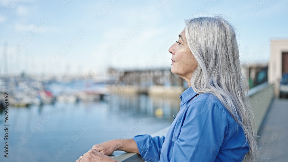 Middle age grey-haired woman looking to the side with serious expression at seaside
