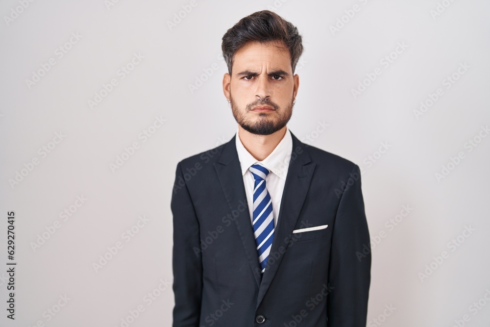 Young hispanic man with tattoos wearing business suit and tie skeptic and nervous, frowning upset because of problem. negative person. Young hispanic man with tattoos wearing business suit and tie skeptic and nervous, frowning upset because of problem. negative person.