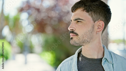 Young hispanic man looking to the side with serious expression at park