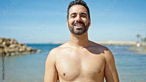 Young hispanic man tourist smiling confident standing shirtless at the beach
