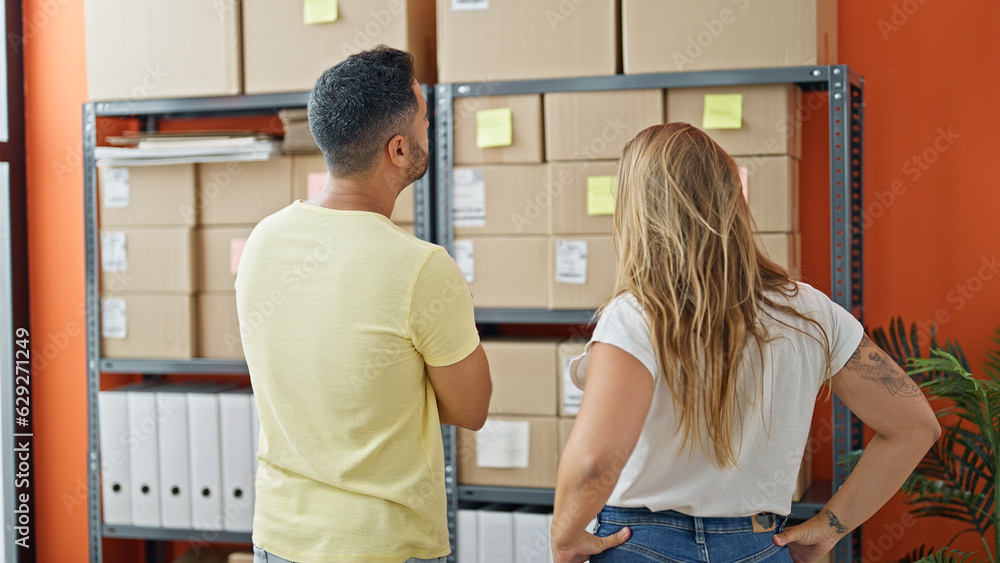 Man and woman ecommerce business workers looking packages on shelving at office Man and woman ecommerce business workers looking packages on shelving at office
