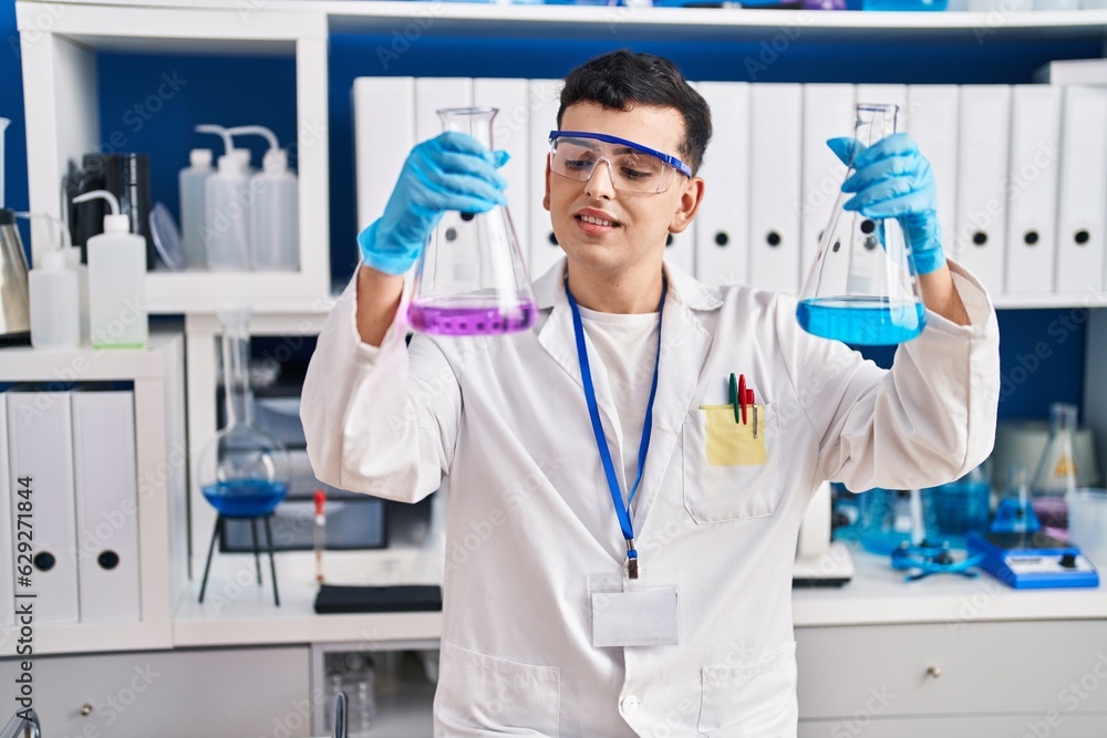 Young non binary man scientist smiling confident measuring liquid at laboratory Young non binary man scientist smiling confident measuring liquid at laboratory