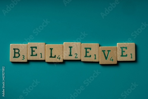 Wooden letters spelling the word believe on a blue background.