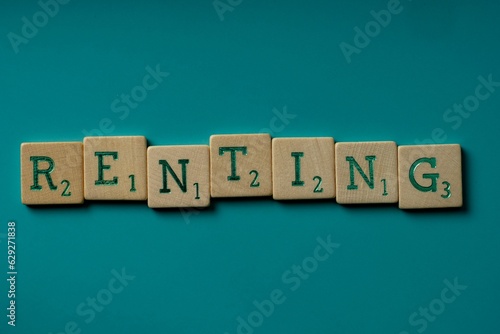 Wooden letters spelling the word renting on a blue background.