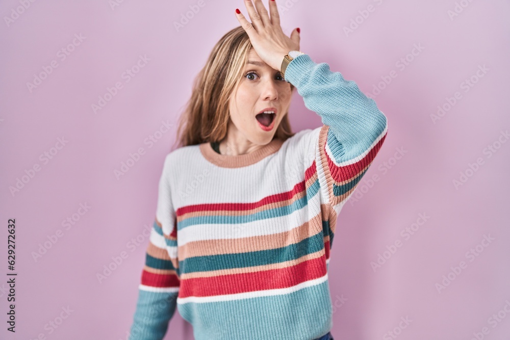 Young blonde woman standing over pink background surprised with hand on head for mistake, remember error. forgot, bad memory concept. Young blonde woman standing over pink background surprised with hand on head for mistake, remember error. forgot, bad memory concept.
