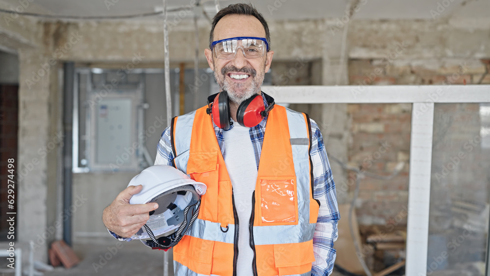 Middle age man builder smiling confident holding hardhat at construction site Middle age man builder smiling confident holding hardhat at construction site