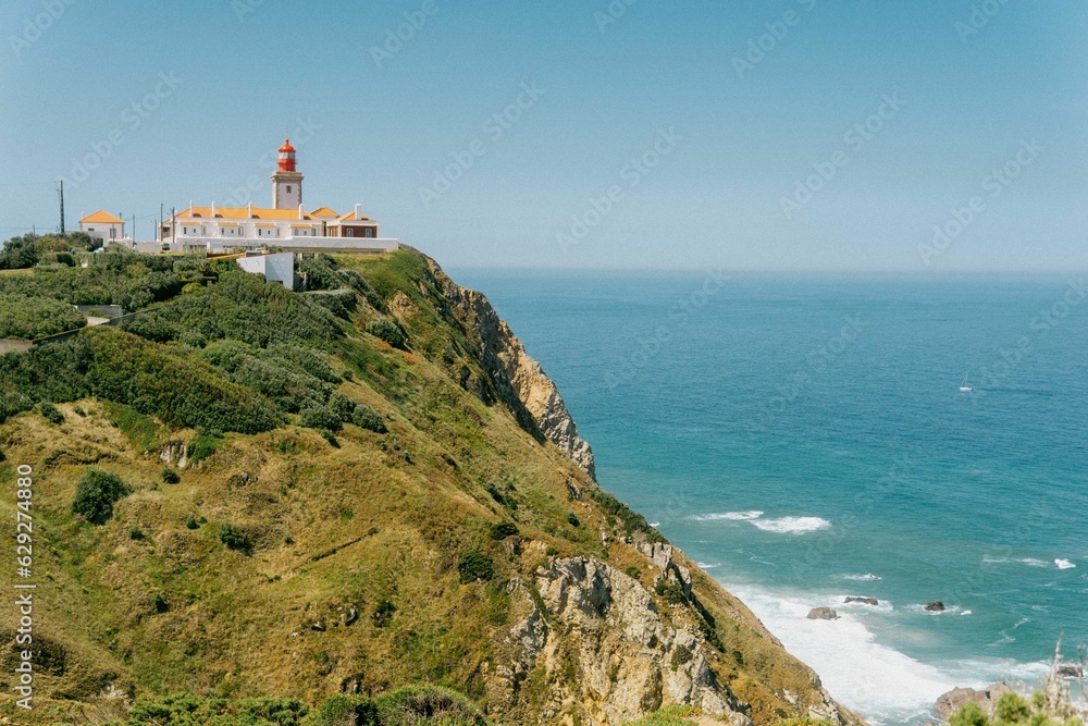 Idyllic coastal landscape featuring a building perched on top of green and rocky cliffs