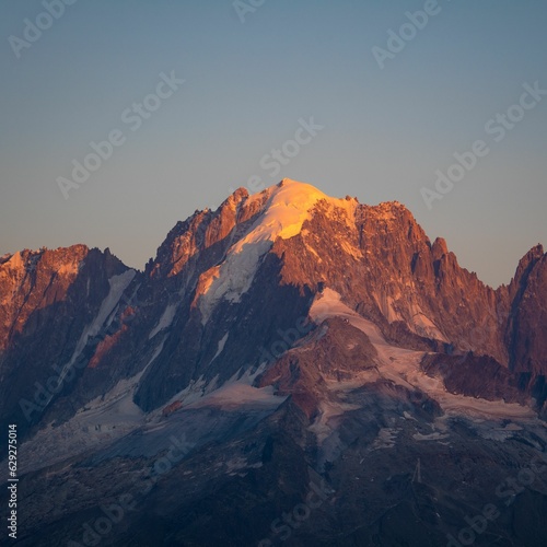 Striking view of a snow-capped mountain illuminated by the fading golden light of a setting sun