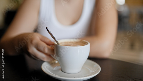 Young beautiful hispanic woman drinking coffee sitting on the table at cafeteria