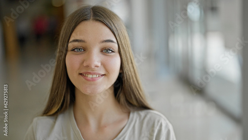 Young beautiful girl smiling confident sitting on table at library
