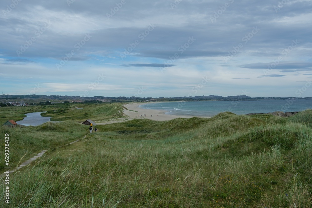 Group of people hiking on Brusand Beach, Norway on a cloudy summer day Group of people hiking on Brusand Beach, Norway on a cloudy summer day
