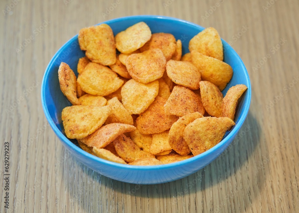 Wooden table with a blue bowl full of potato chips Wooden table with a blue bowl full of potato chips