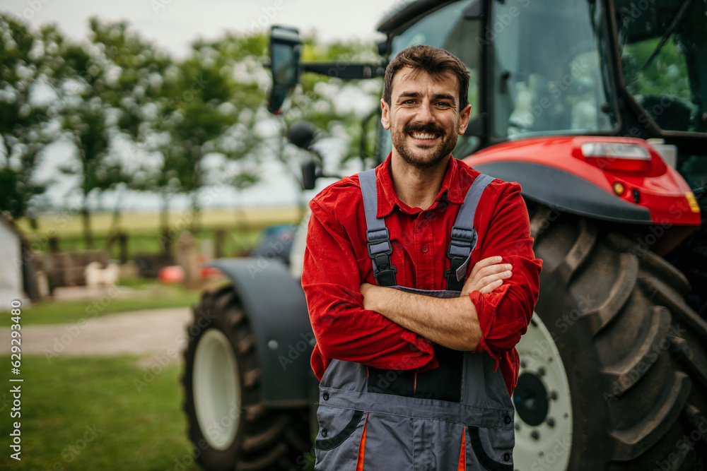 Portrait of a smiling engineer in a working suit standing in front of agricultural machinery. Portrait of a smiling engineer in a working suit standing in front of agricultural machinery.