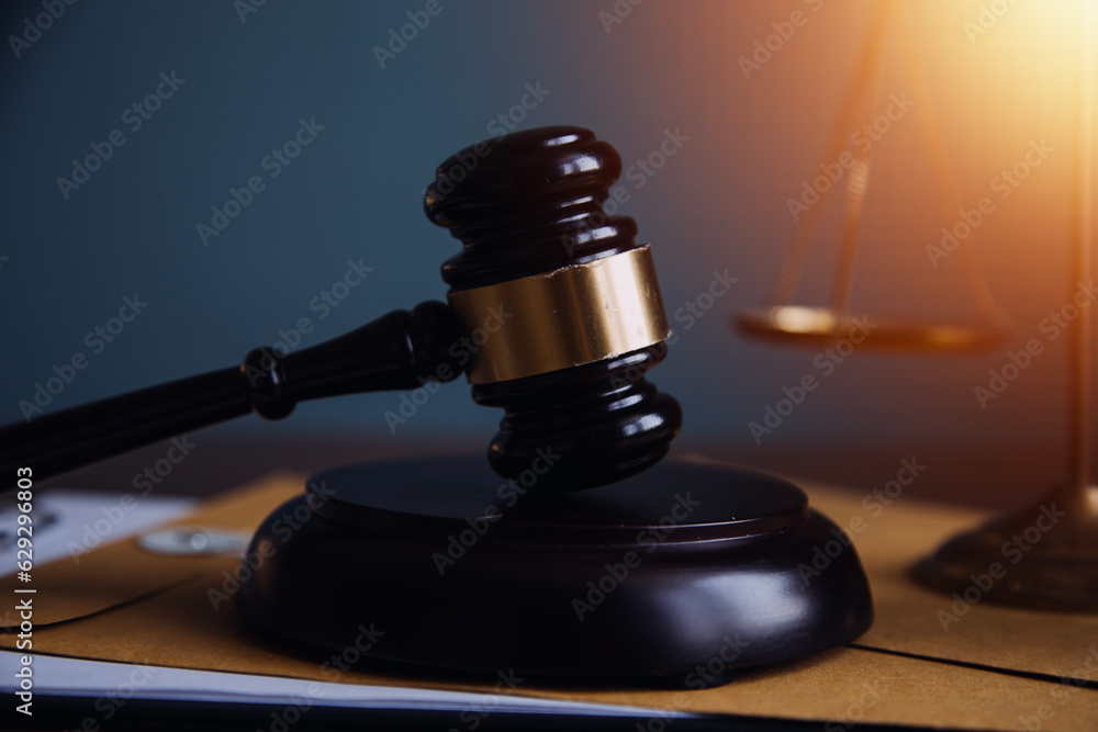 Justice and law concept.Male judge in a courtroom with the gavel, working with, computer and docking keyboard, eyeglasses, on table in morning light Justice and law concept.Male judge in a courtroom with the gavel, working with, computer and docking keyboard, eyeglasses, on table in morning light