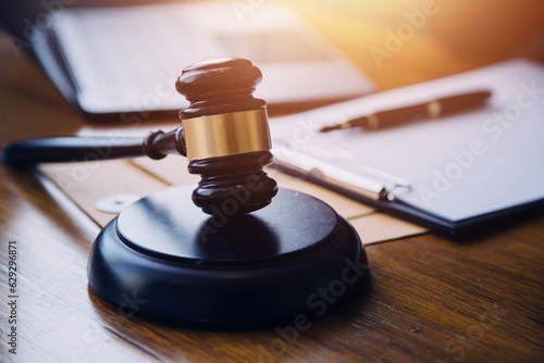 Justice and law concept.Male judge in a courtroom with the gavel  working with  computer and docking keyboard  eyeglasses  on table in morning light