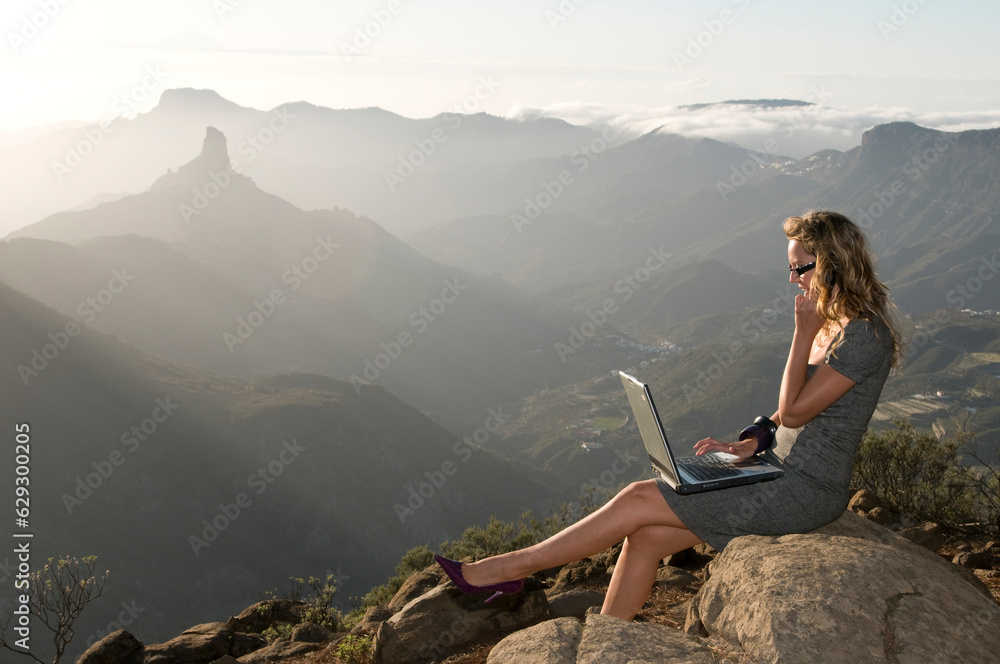Woman working with portatil laptop in the forest and talking by phone
