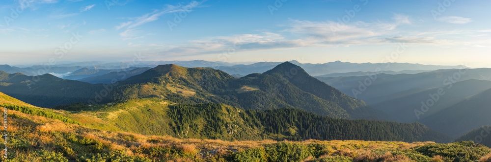 Panorama of autumn morning in the mountains. The rising sun illuminates the magnificent mountain landscape