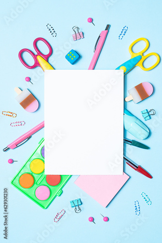 Bright composition with colorful stationery and blank paper sheet on light blue background top view, copy space for your design. Back to school concept.