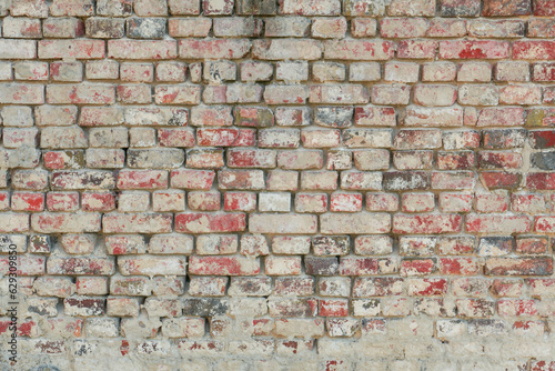 Zdjęcie przedstawiające teksturę utworzoną przez cegły ułożone w równych rzędach w murze. Cegły częściowo pokryte są zaprawą murarską. Stanowią one element starej budowli.