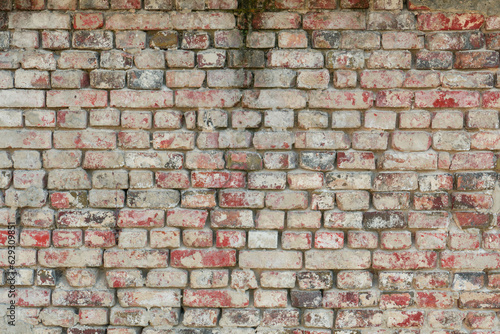 Zdjęcie przedstawiające teksturę utworzoną przez cegły ułożone w równych rzędach w murze. Cegły częściowo pokryte są zaprawą murarską. Stanowią one element starej budowli.