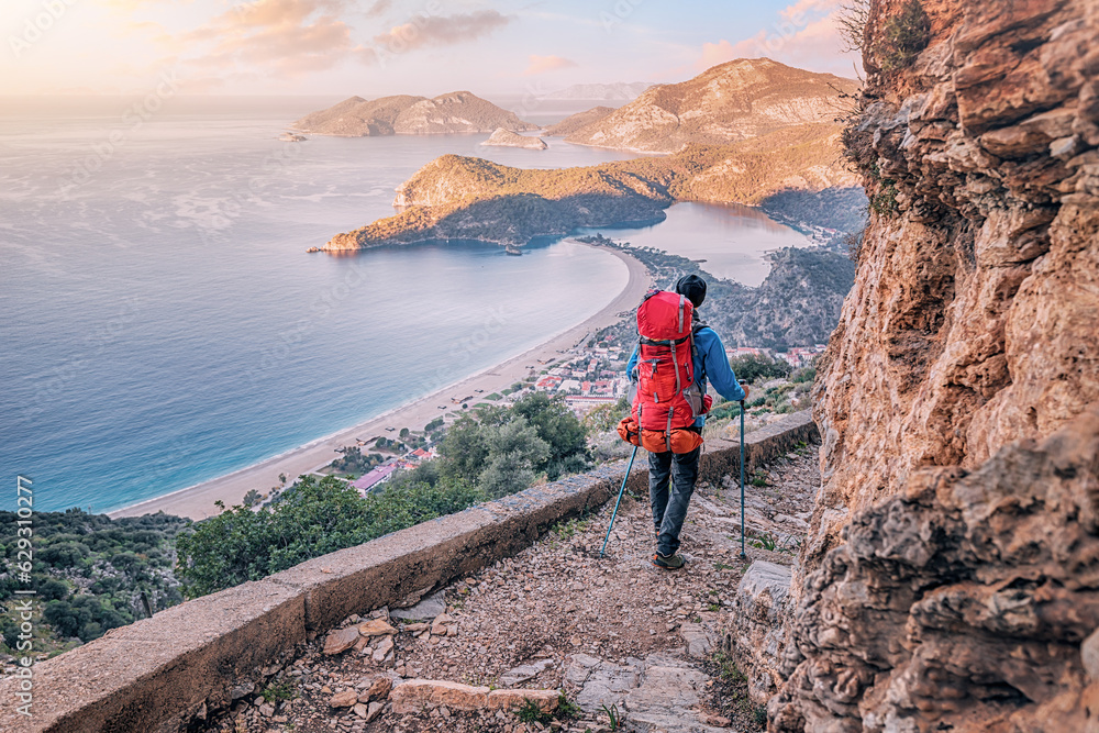 Happy hiker man with trekking backpack at a viewpoint of Lycian Way trail in Oludeniz, Fethiye. Travel and adventure in Turkey