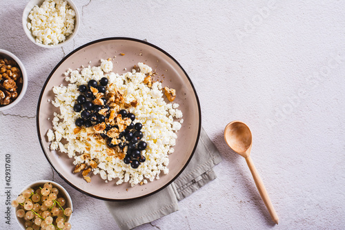 Foto Soft cottage cheese with blackcurrant and walnuts on a breakfast plate top view