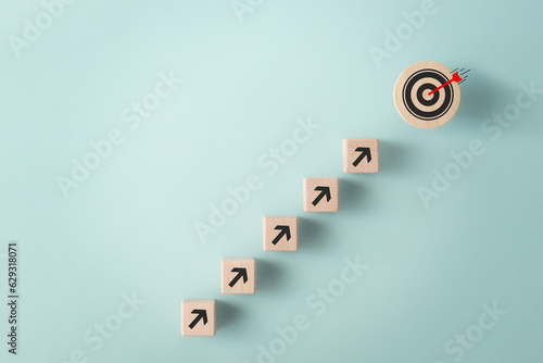 Obraz na płótnie Business growth, objective goal achievement concept. Wooden block with target aiming dart board and arrow up on blue background top view w salonie
