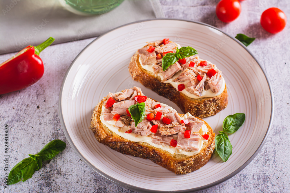 Toast with canned tuna, cream cheese, peppers and herbs on a plate