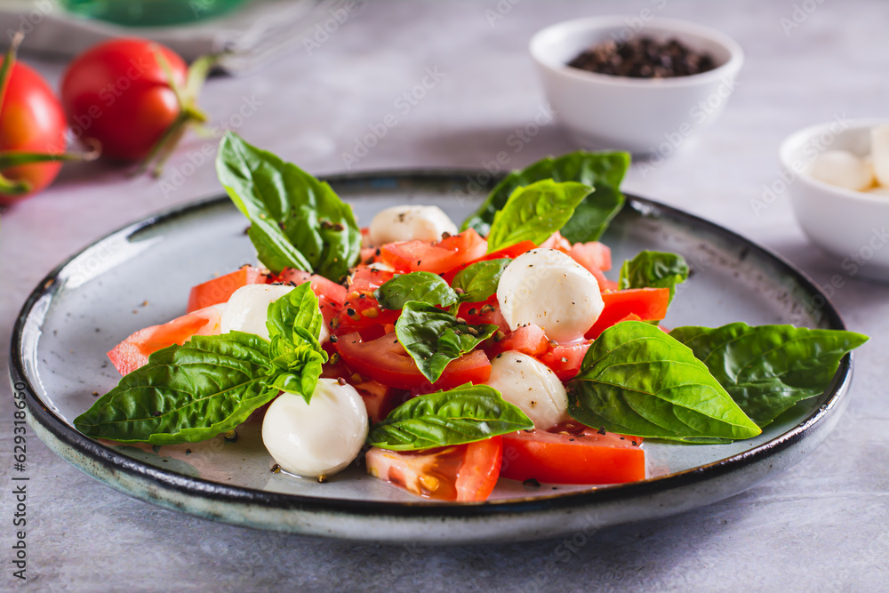 Caprese salad with tomatoes, mozzarella, basil and olive oil on a plate