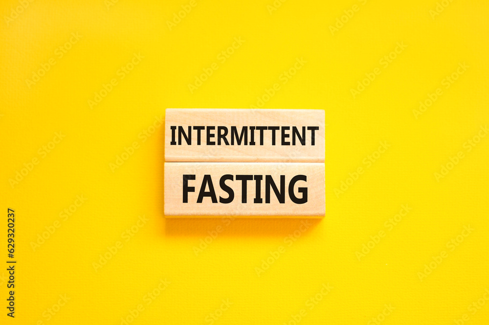 Intermittent fasting symbol. Concept words Intermittent fasting on beautiful wooden block. Beautiful yellow table yellow background. Healthy lifestyle intermittent fasting concept. Copy space. Intermittent fasting symbol. Concept words Intermittent fasting on beautiful wooden block. Beautiful yellow table yellow background. Healthy lifestyle intermittent fasting concept. Copy space.