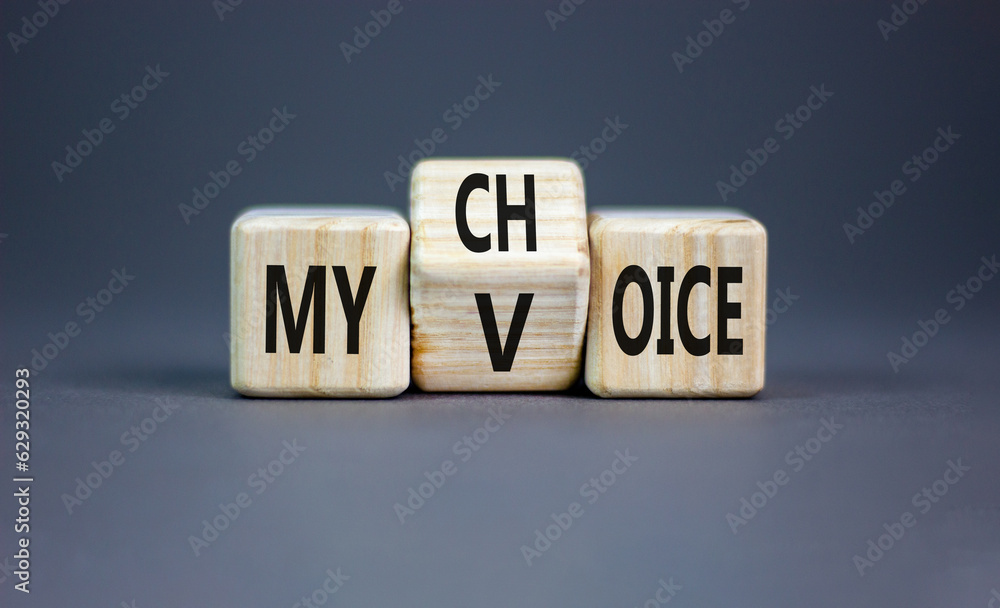 My voice and choice symbol. Businessman turns wooden cubes and changes the concept word my choice to voice. Beautiful grey table grey background, copy space. Business and my voice choice concept. My voice and choice symbol. Businessman turns wooden cubes and changes the concept word my choice to voice. Beautiful grey table grey background, copy space. Business and my voice choice concept.
